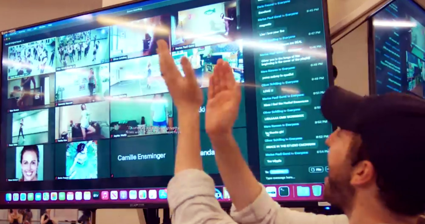 Image of a zoom screen showing dancers joining a dance class virtually - the teacher is addressing them and clapping.